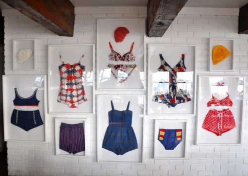 Vintage swimsuits displayed on the wall of a coastal home