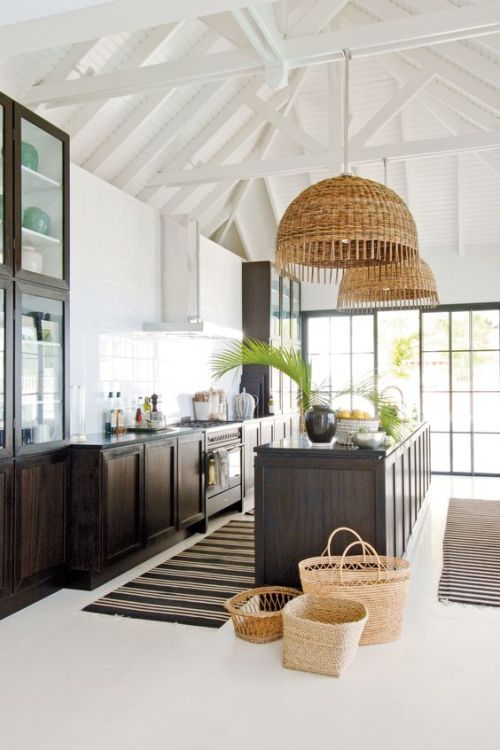 Coastal kitchen with large wicker pendant lights and dark cabinets with white walls